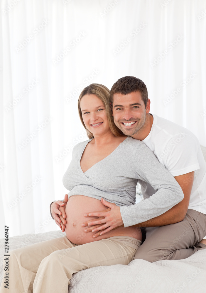 Cute pregnant woman touching her belly with her husband in the b Cute pregnant woman touching her belly with her husband in the b