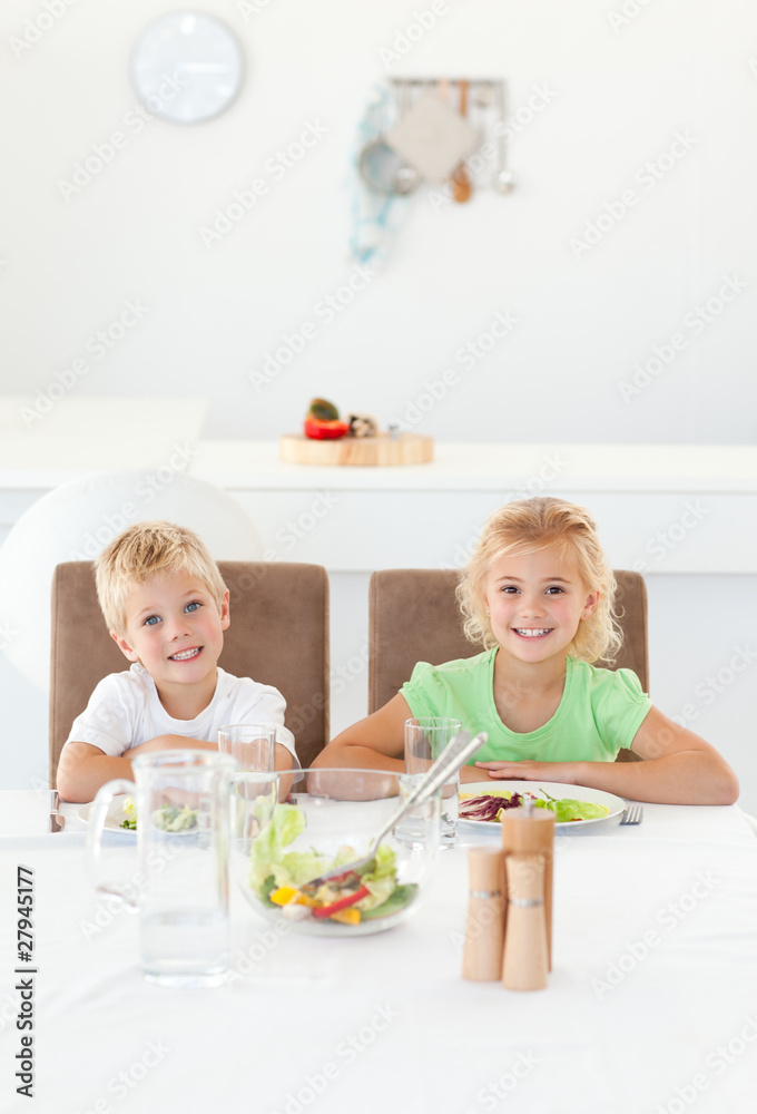 Adorable siblings eating a salad together in the kitchen