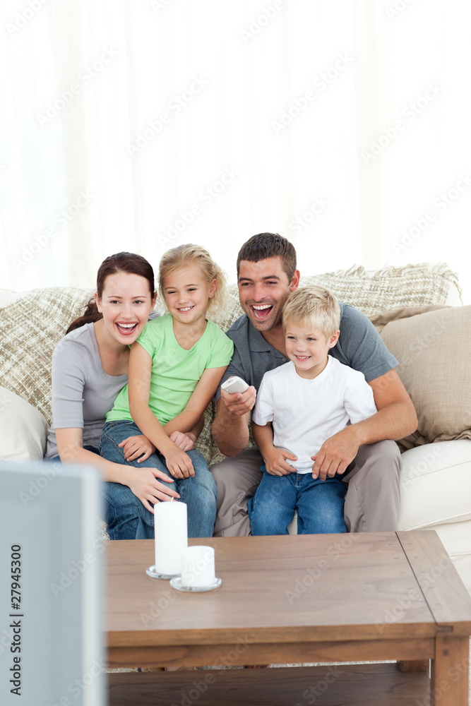 Happy family laughing while watching television sitting on the s