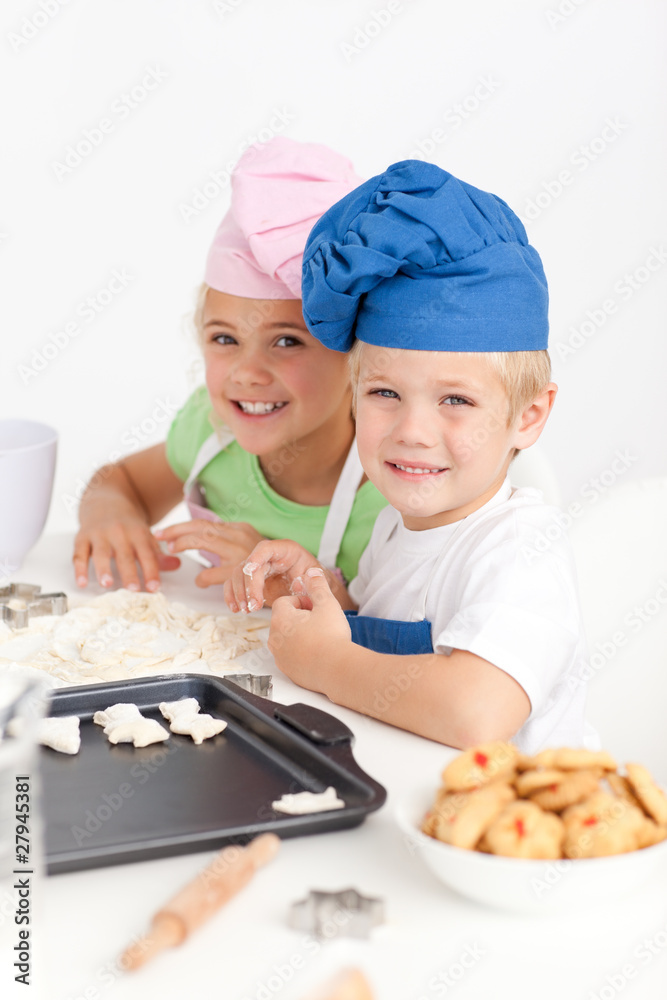 Adorable siblings kneading together a dough in the kitche Adorable siblings kneading together a dough in the kitche