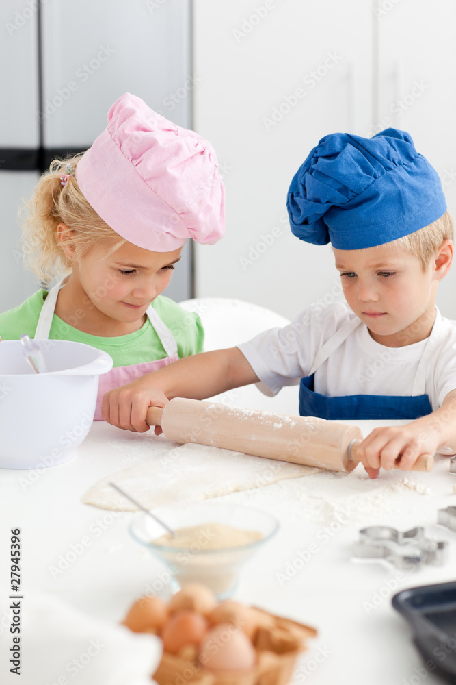 Little girl looking at her serious brother using a rolling pin Little girl looking at her serious brother using a rolling pin