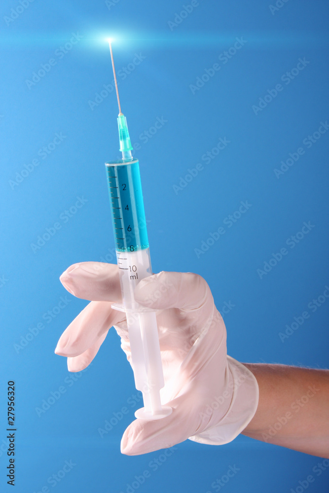 Syringe in doctors hand over blue background Syringe in doctors hand over blue background