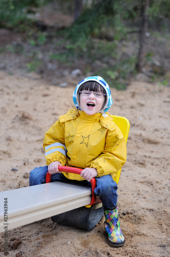 Adorable toddler girl in yellow rain coat on swing Adorable toddler girl in yellow rain coat on swing