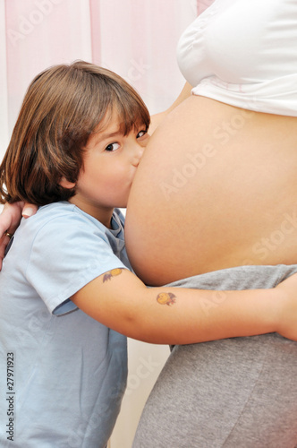 Young boy kissing pregnant belly