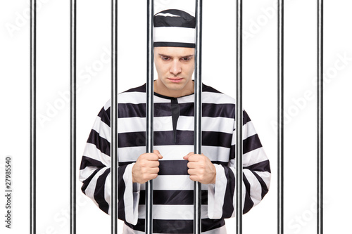 A sad prisoner in jail holding bars Fototapet