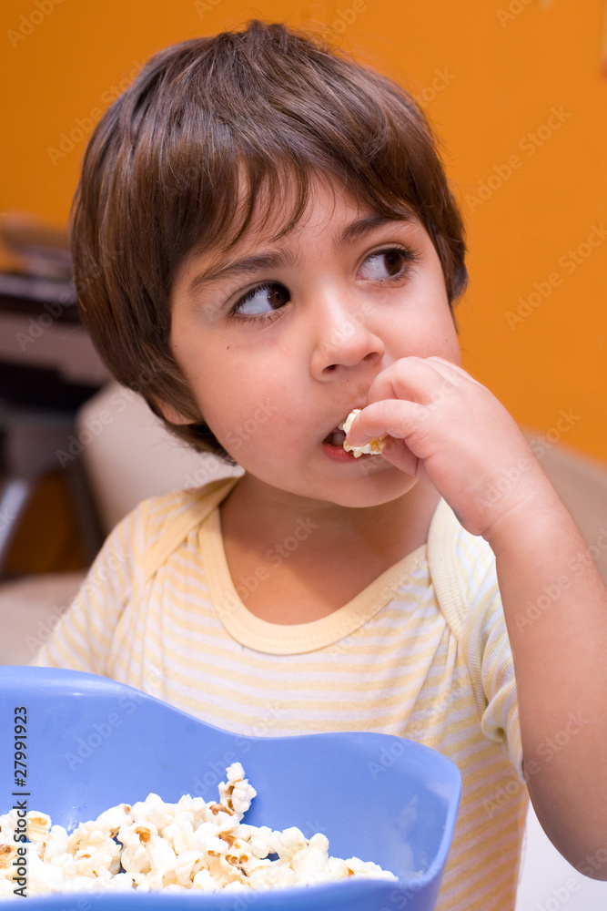 bambino mangia popcorn davanti alla tv