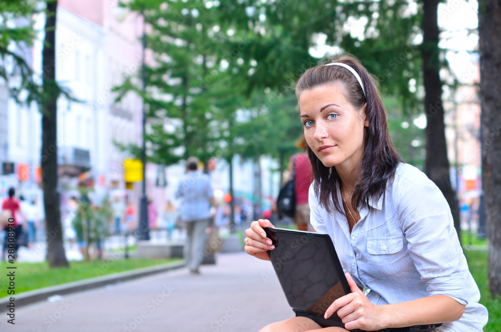 beautiful woman is sitting in city with laptop and looking at ca beautiful woman is sitting in city with laptop and looking at ca