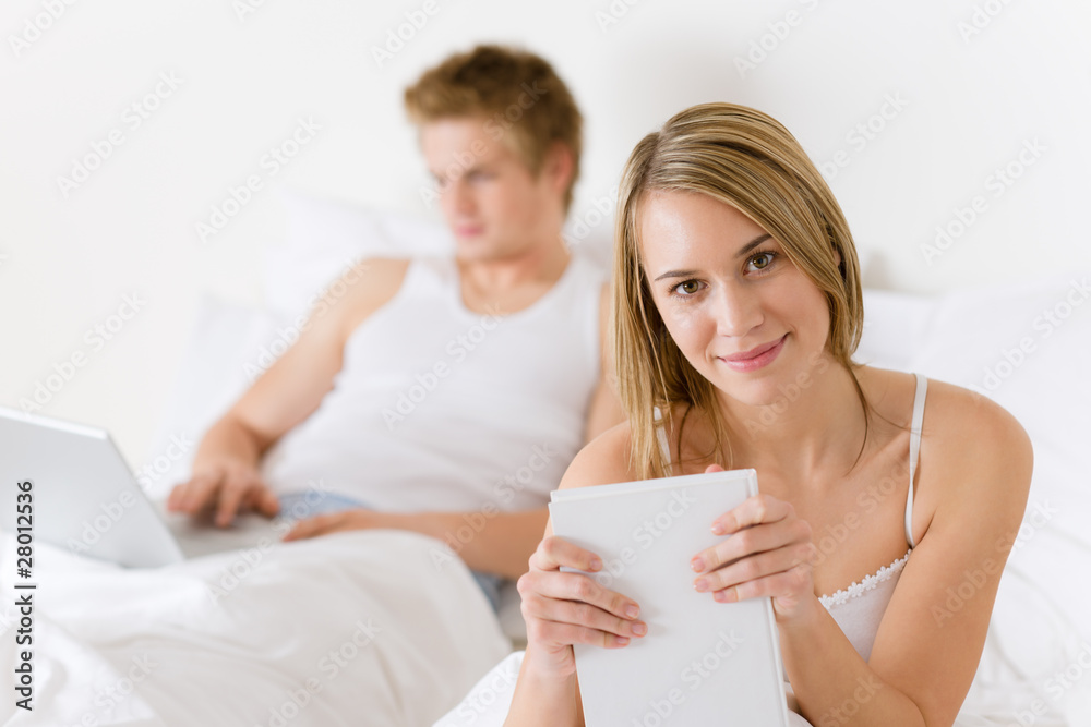Bedroom - young couple with laptop and book Bedroom - young couple with laptop and book