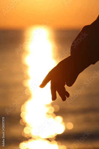 Silhouette of hand of child  and sun way on salt water