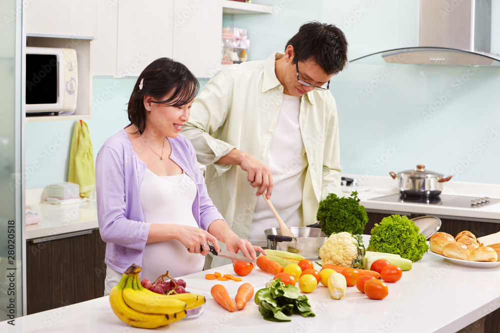 Asian couple busy in kitchen