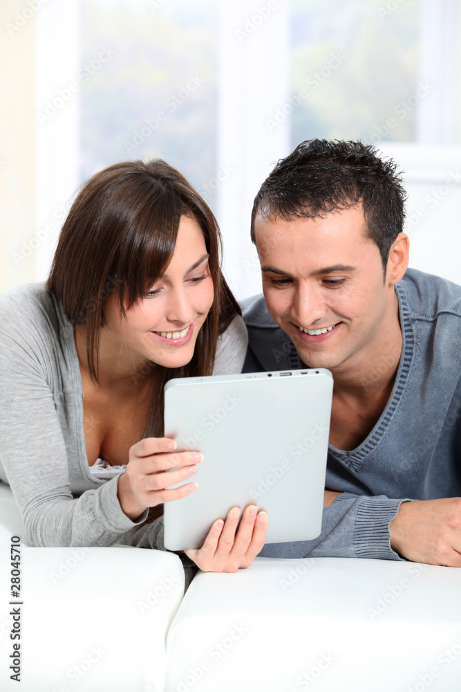Couple sitting on sofa with electronic pad Couple sitting on sofa with electronic pad