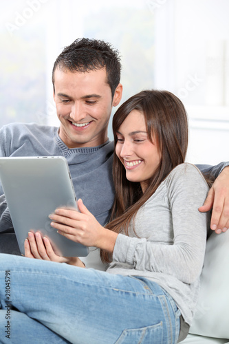 Couple sitting on sofa with electronic pad