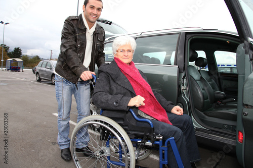 Young man assisting senior woman in wheelchair © goodluz