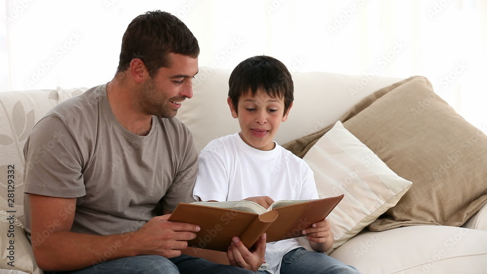 Father and son looking at a book on the sofa