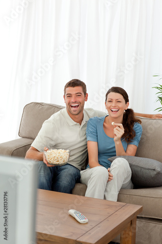 Cute couple eating pop corn while watching television on sofa © WavebreakMediaMicro