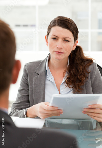 Serious businesswoman questionning a man during a meeting photo