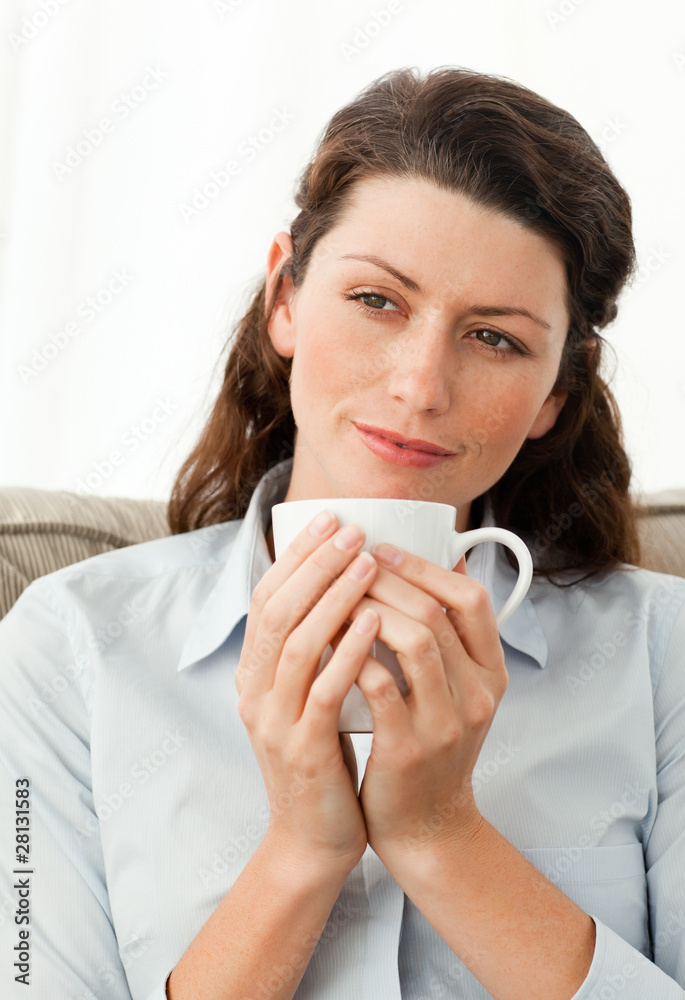 Pretty woman holding a cup of coffee sitting on the sofa Pretty woman holding a cup of coffee sitting on the sofa