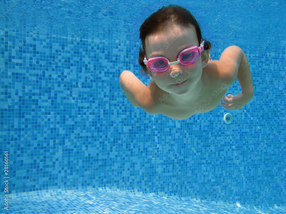 Naklejka premium Child swimming underwater in the pool