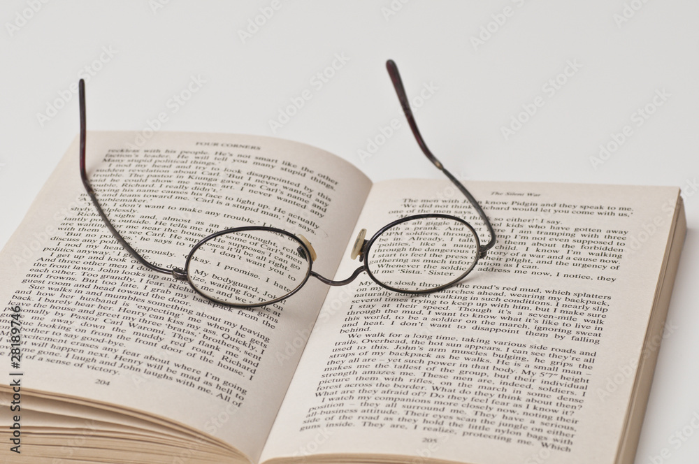 Glasses with black rounded frame on open book Glasses with black rounded frame on open book