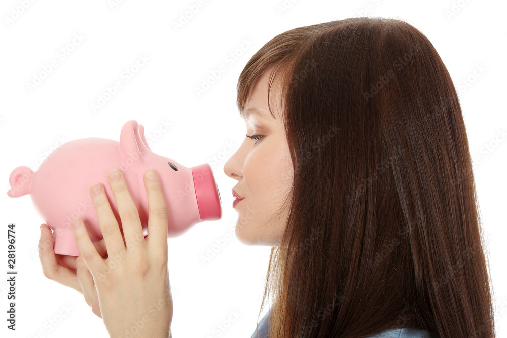 Young teen woman kissing a piggy bank