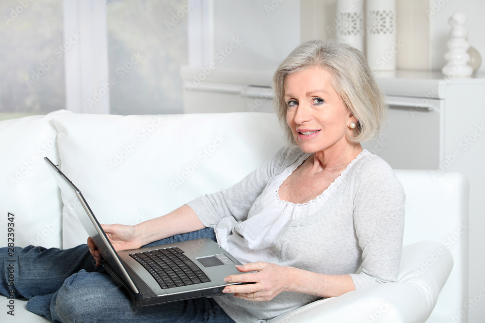 Senior woman sitting in sofa with laptop computer Senior woman sitting in sofa with laptop computer