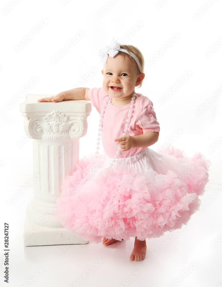 Baby girl wearing pettiskirt tutu and pearls standing next to a