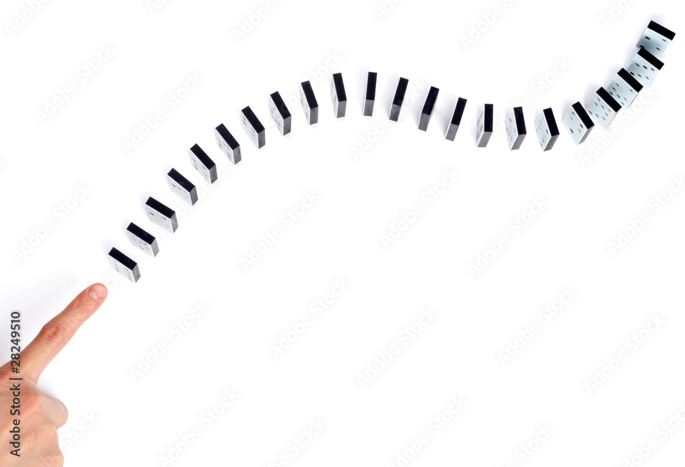 Hand ready to push domino pieces to cause chain reaction Hand ready to push domino pieces to cause chain reaction