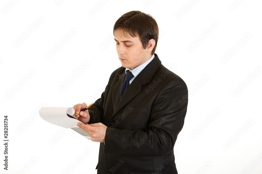 Serious young businessman making notes in document Serious young businessman making notes in document