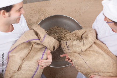 zwei bäcker schütten korn in die mühle photo