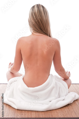 Nude women sitting meditating with towel around her waist