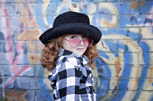 Red haired little girl in front of brick wall