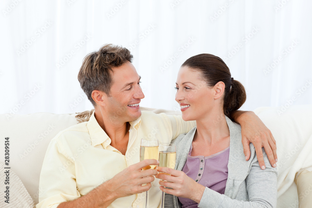 Cute couple drinking champagne while relaxing on the sofa Cute couple drinking champagne while relaxing on the sofa