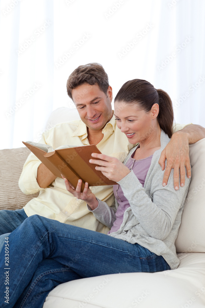 Happy couple looking at pictures on a photo album while relaxing