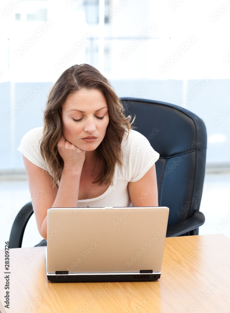 Thoughtful businesswoman working on laptop at a table Thoughtful businesswoman working on laptop at a table