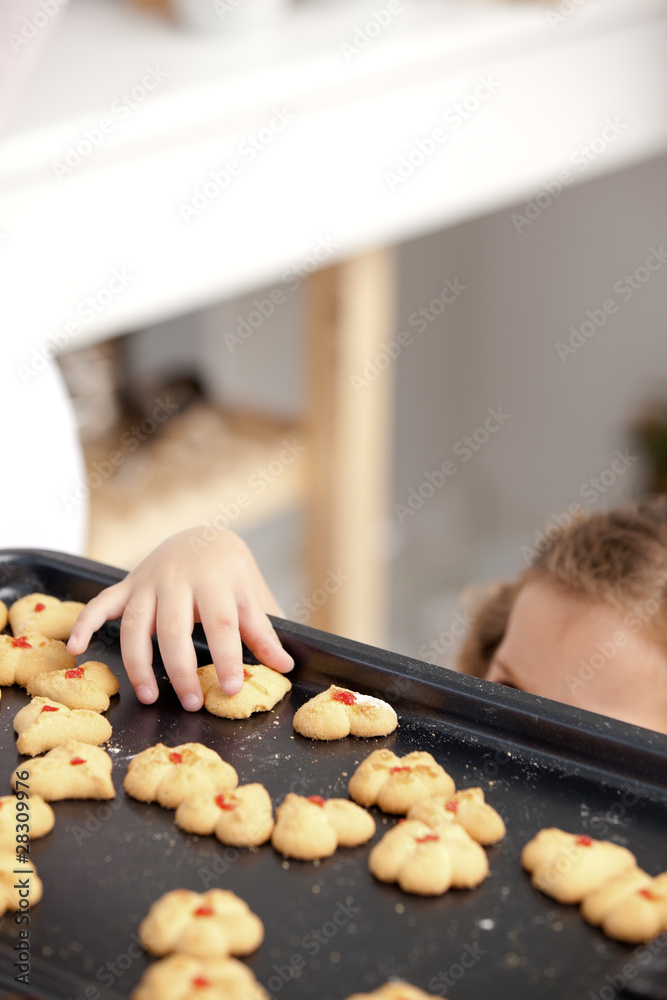 Close up of a little girl taking a cookie in the kitchen