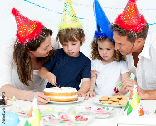 Cute little boy cutting a birthday cake for his family