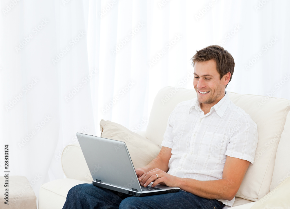 Handsome man working on his laptop on the sofa