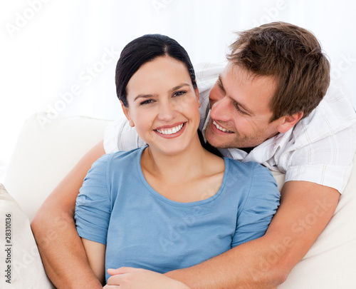 Passionate man hugging his girlfriend while relaxing on the sofa