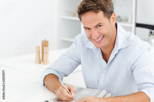 Happy man doing a crossword sitting at a table