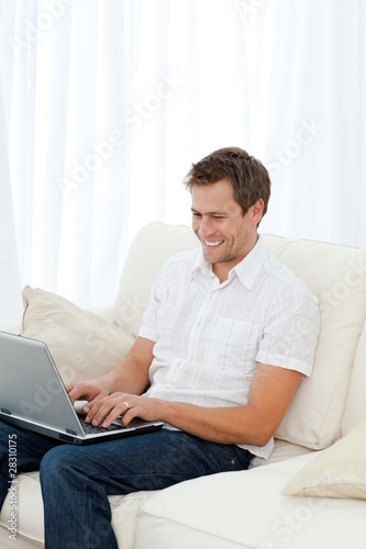 Man laughing while working on his laptop on the sofa © WavebreakMediaMicro