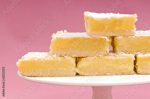 Freshly baked lemon squares on a white cake stand