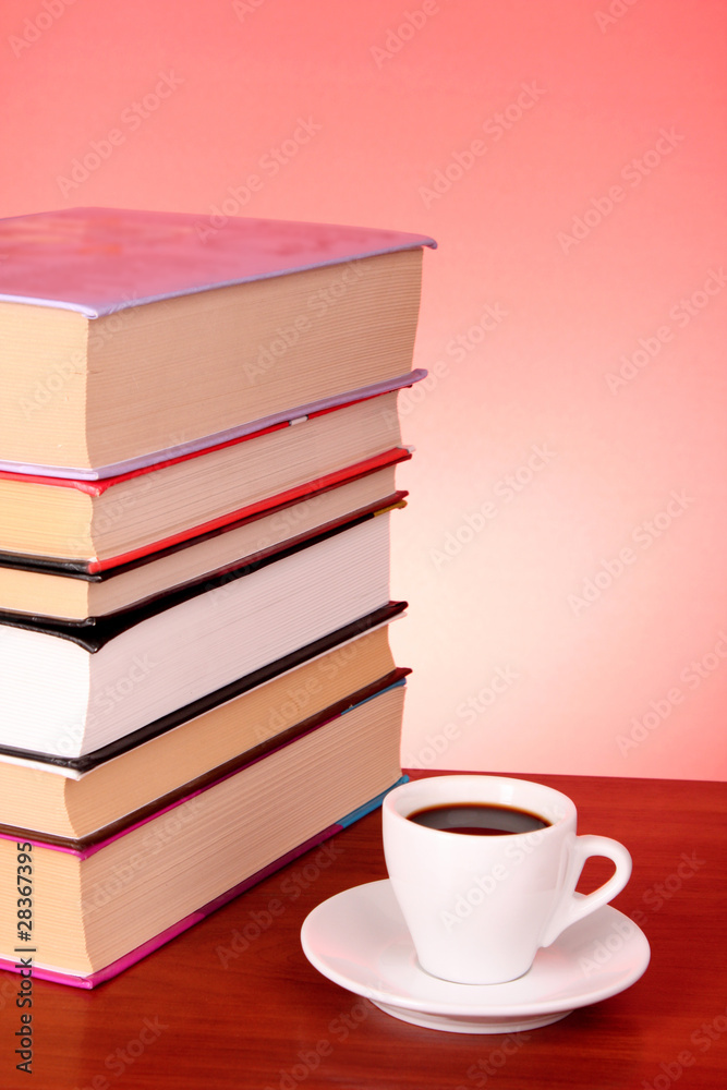 Books pile and cup of coffee on the table and red background Books pile and cup of coffee on the table and red background