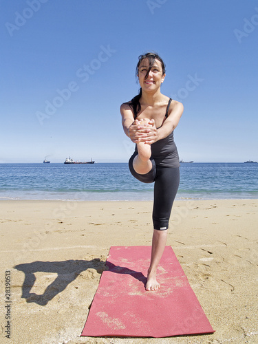 Bikram yoga dandayamana janushirasana frontal pose at beach photo