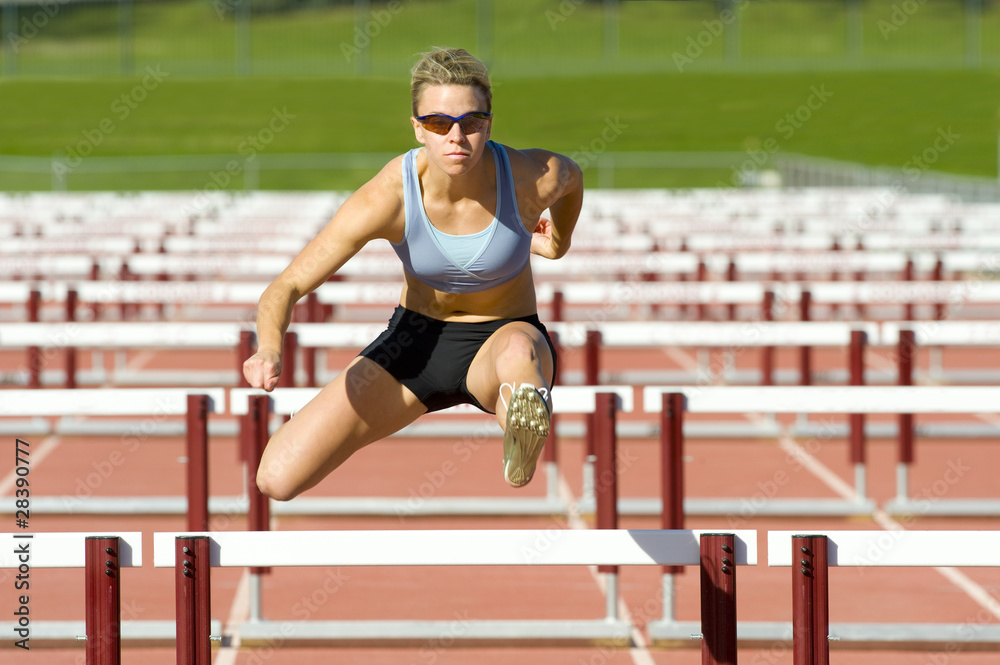 Fototapeta premium Athlete Jumping over Hurdles