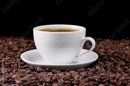 ceramic cup of coffee and beans on black