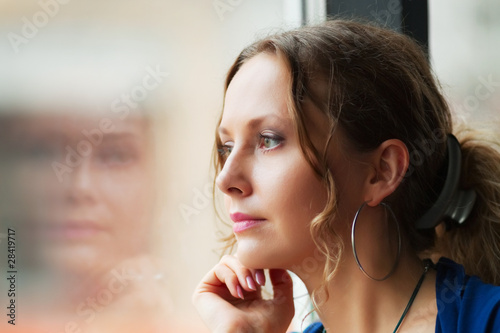 Sad young woman looking through window photo