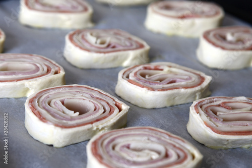 Raw puff pastry rolls with ham, salami and cheese