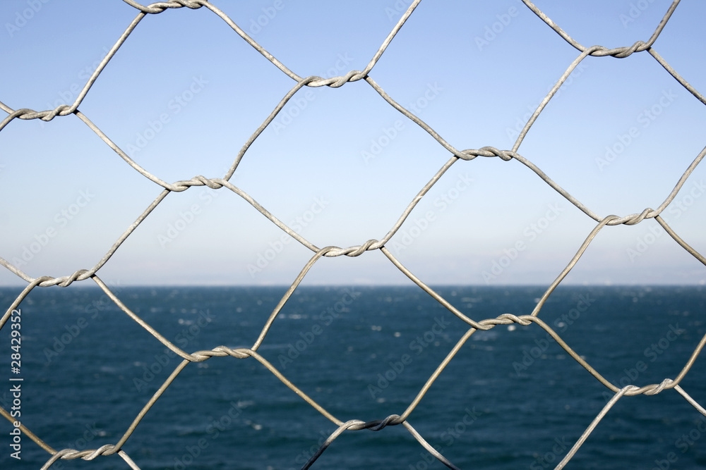 Fototapeta premium Detail of wire netting in front of sea