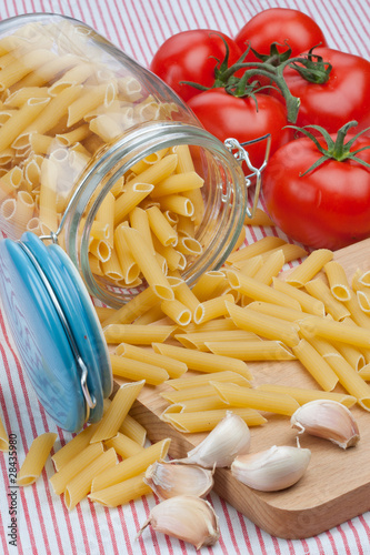 Glass jar and penne rigate raw pasta