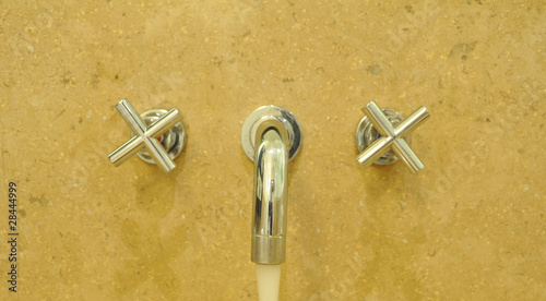 Metallic Faucet on yellow Ceramic wall with water drop © naipung